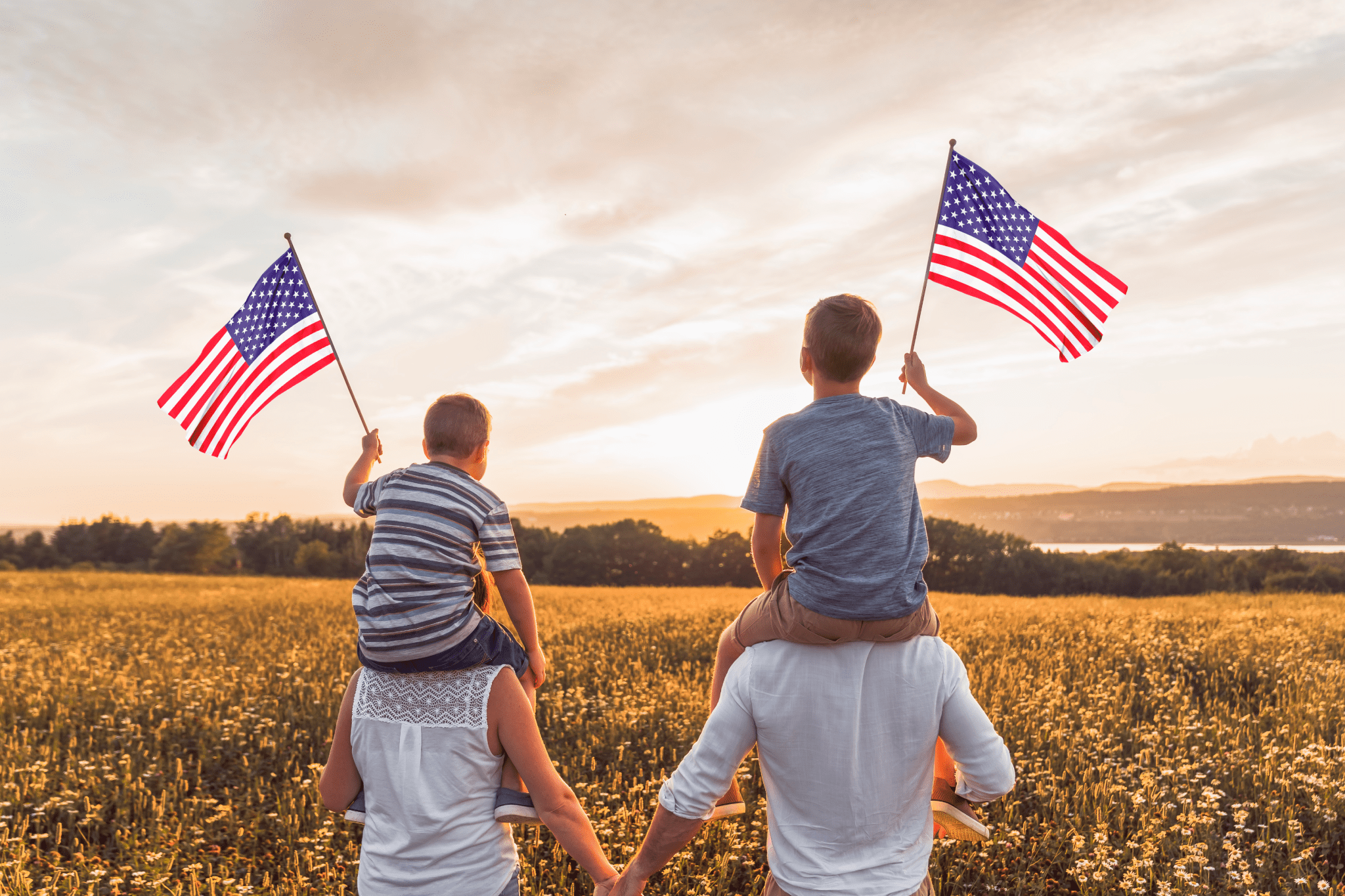 j1 A family holding american flags in the middle of a field.